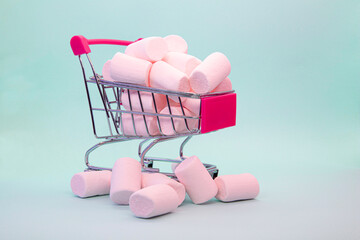 Small shopping cart with marshmallows on a blue background. Shopping. Lots of products