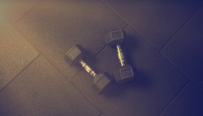 Metal rubberized dumbbells on a dark black floor. Bodybuilding and Fitness