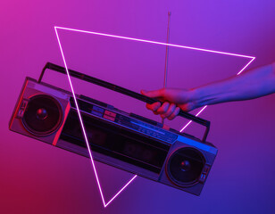 Hand holding retro radio tape recorder. in blue-red neon gradient light with triangle. Pop culture....