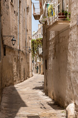 malownicza uliczka z balkonami pełnymi kwiatów. Słoneczny letni dzień. Monopoli, Puglia, Włochy - obrazy, fototapety, plakaty