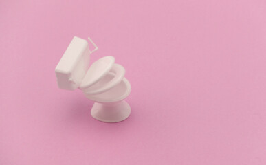 Mini white toilet on pink background. Minimalism.