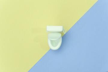 Mini white toilet on yellow blue background. Minimalism. Top view