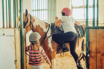 saddled brown horse in stables and child.