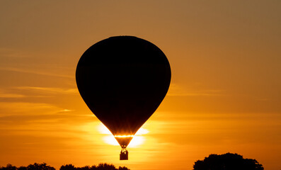 hot air balloon with travelers flying at sunset