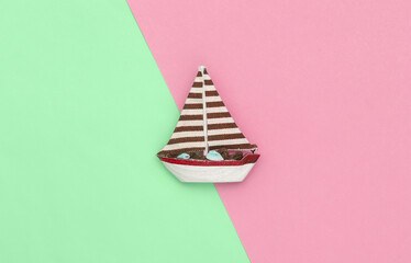 Sailboat on a green pink background. Travel minimalism concept. Top view. Flat lay