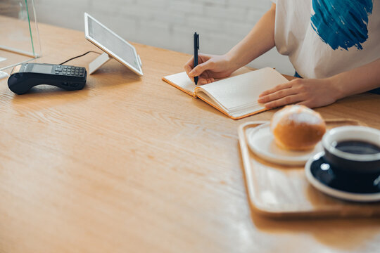 Female barista writing in notebook in coffee shop