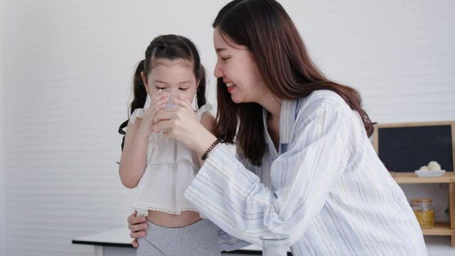 Mother and daughter happy to drink fresh milk in kitchen at home. Milk is beneficial for growth of body for children. family living together with love. Weekend activity happy family lifestyle concept