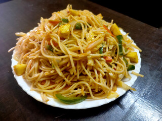 spaghetti vegetarian soft cheese/paneer noodles  meal in white plate isolated  on dark brown wooden table top,dish,veg
