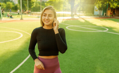 Cheerful attractive sport woman listening to music with headphones outdoors