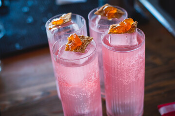 Bartender in front of beautiful row of different coloured alcohol cocktails on a party in a bar, martini, vodka, and others on decorated catering banquet table on open air event