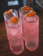 Bartender in front of beautiful row of different coloured alcohol cocktails on a party in a bar, martini, vodka, and others on decorated catering banquet table on open air event