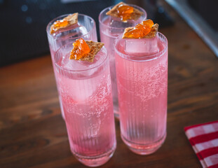 Bartender in front of beautiful row of different coloured alcohol cocktails on a party in a bar, martini, vodka, and others on decorated catering banquet table on open air event