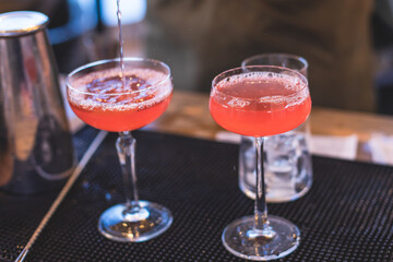 Bartender in front of beautiful row of different coloured alcohol cocktails on a party in a bar, martini, vodka, and others on decorated catering banquet table on open air event