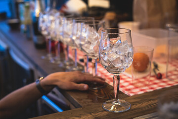 Bartender in front of beautiful row of different coloured alcohol cocktails on a party in a bar, martini, vodka, and others on decorated catering banquet table on open air event