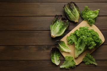 Different sorts of lettuce on wooden table, flat lay. Space for text
