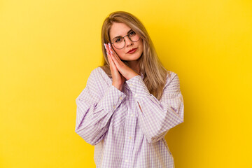 Young russian woman isolated on yellow background yawning showing a tired gesture covering mouth with hand.