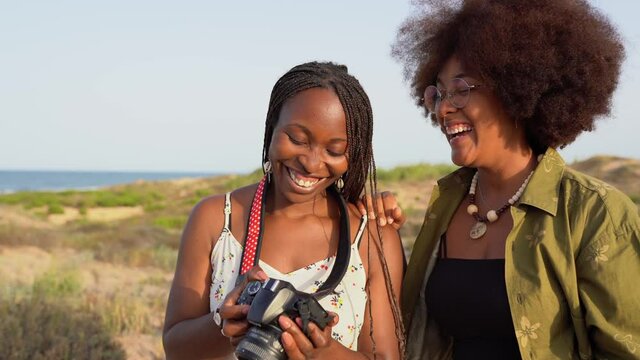 Happy black girlfriends with photo camera in summer nature