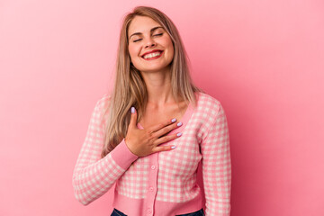 Young russian woman isolated on pink background laughs out loudly keeping hand on chest.
