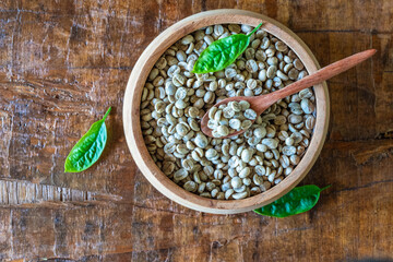 unroasted green coffee beans in a wooden bowl