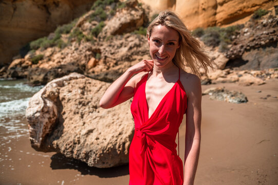 Charming happy woman in red dress on beach