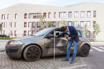 Side view of brunette male auto insurance adjuster inspecting a vehicle that has been in an...