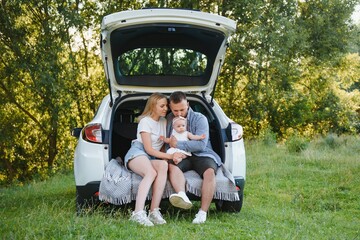 Family with kid sitting in car trunk