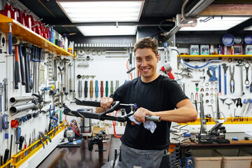 Male mechanic wiping bicycle frame in garage