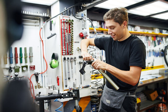 Smiling man repairing bicycle fork in garage