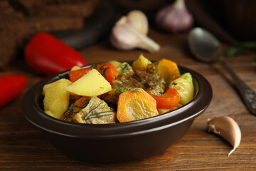 Tasty cooked dish with potatoes in earthenware on wooden table