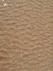 Fototapeta na wymiar Wet sand surface ocean wave water ripples