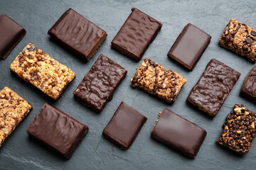 Different tasty protein bars on black table, flat lay
