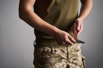 Mid-section shot of a military man sharpening his pocket knife