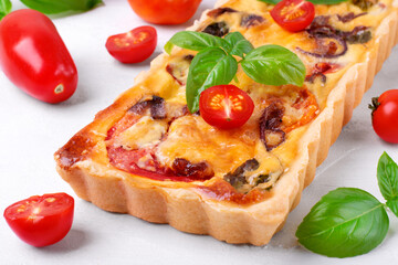 Quiche with egg, tomato, caramelized onion, basil and cheese. French cuisine pie