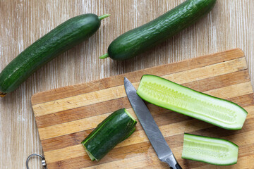 Top view of whole fresh cucumbers and cutted on the wooden cutting board