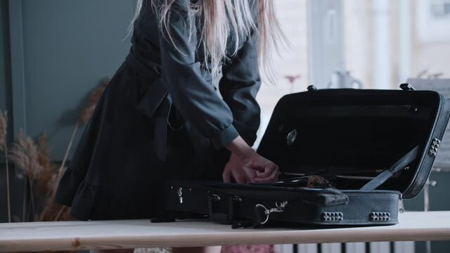 Young blonde woman musician takes a violin out of the case in the class