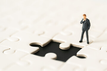 Miniature people Group Business man mini figures standing thinking on Jigsaw Puzzle white background copy space using as thinking business plan and how to solve problem Strategy Planning concepts