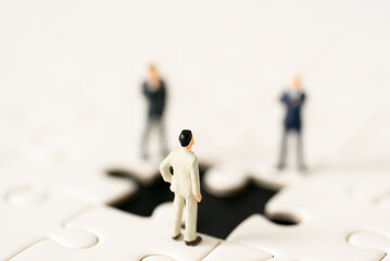 Miniature people Group Business man mini figures standing thinking on Jigsaw Puzzle white background copy space using as thinking business plan and how to solve problem Strategy Planning concepts