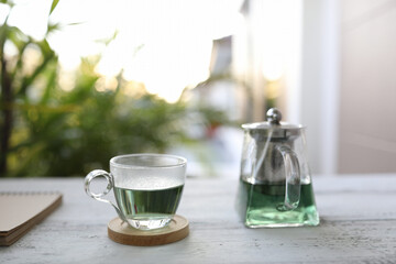 butterfly pea tea in glass cup and glass teapot with notebook on grunge table
