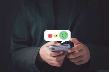 Satisfaction survey and customer service concept. Hand touching satisfaction on smartphone and give scores.Give very satisfied rating with smiley icon.
