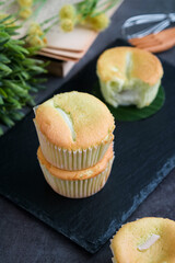 High angle view of coconut pandanus muffin on a black plate with fork and mini pastry whisk in background. It's a fusion aroma light cake, green color from natural extract of pandan leaves 