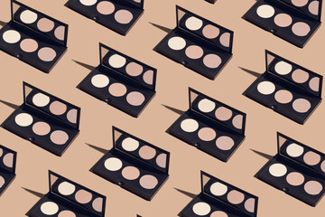 Creative pattern made of facial palette on beige pastel background. Decorative cosmetics and makeup concept. Minimal style composition.