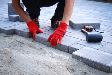 The master in yellow gloves lays paving stones