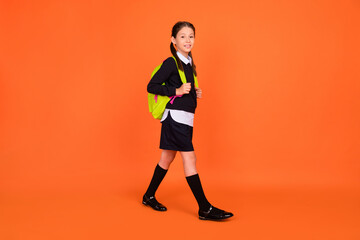 Fototapeta na wymiar Full length photo of pretty cute small schoolgirl go school wear backpack isolated on orange color background
