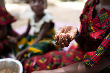Closeup of a young black child's hand holding traditional African food; hunger concept