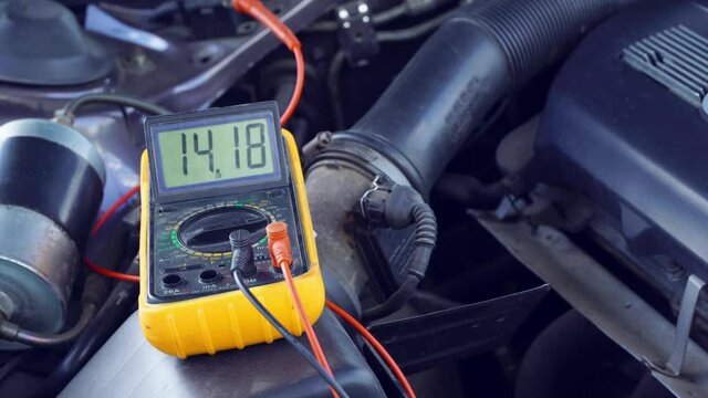 The voltage of the car's starter battery is measured by a multimeter. The voltage is about 14 volts when the generator starts charging the battery. The electrical system works well.