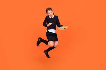 Fototapeta na wymiar Full length body size view of pretty cheerful preteen girl jumping drawing design craft isolated over bright orange color background