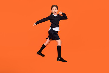 Obraz na płótnie Canvas Full length photo of amazed shocked little girl jump up go walk empty space sale isolated on orange color background