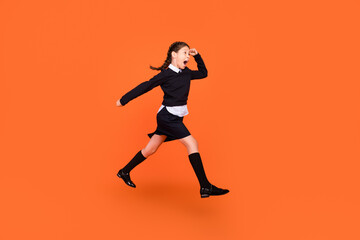 Fototapeta na wymiar Full length body size view of pretty motivated cheery preteen girl jumping running isolated over bright orange color background