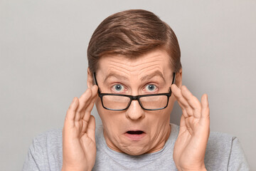 Portrait of shocked man peering over glasses at something unbelievable