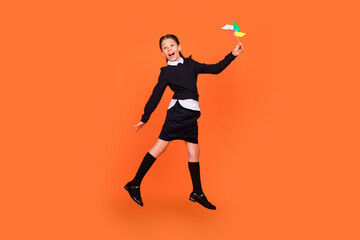 Fototapeta na wymiar Full length body size view of pretty carefree cheery preteen girl jumping playing paper fan isolated over bright orange color background